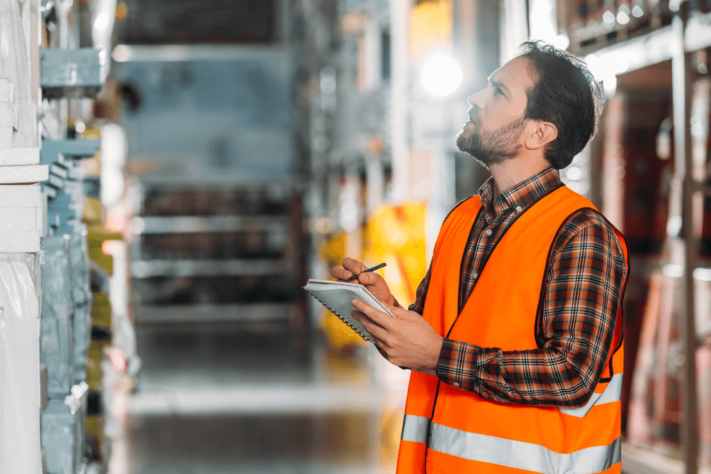 Warehouse worker looking at inventory with clipboard